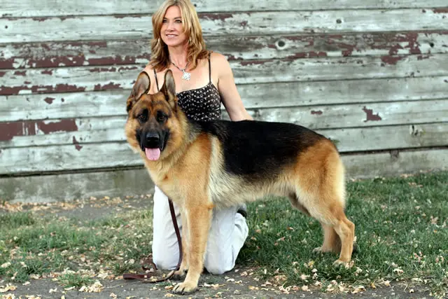 A woman kneeling down next to her dog.
