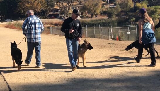 A man walking with his dog in the dirt.